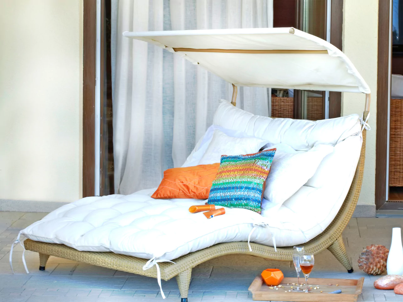 Daybed multifungsi dengan bantal dekoratif di teras yang cerah.